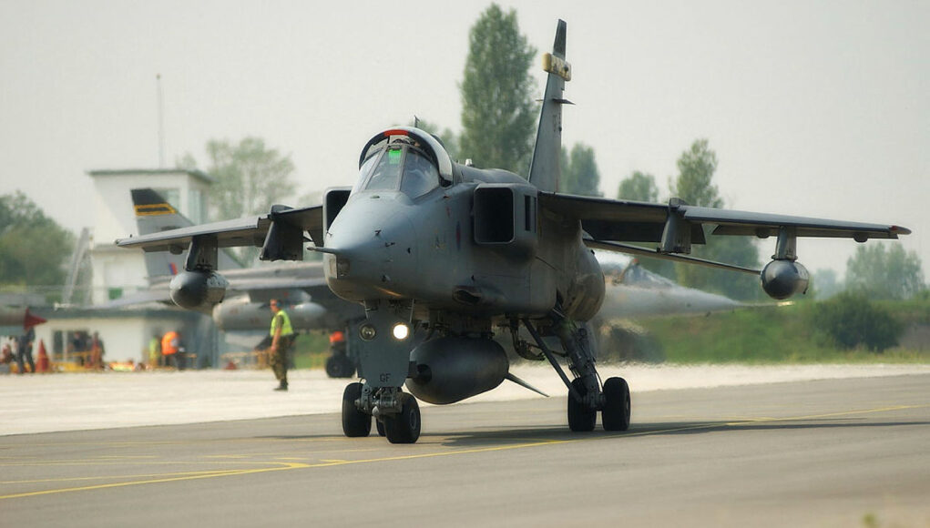 45142075.jpg.iCegqPSCMvUphedfYBMA.ndeIDNBBC- Military jet aircraft taxiing on a runway with ground crew in high-visibility vests in the background at an airbase.