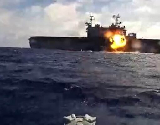 Naval drones attack and sink American assault ship Naval warship at sea with a large explosion and fire on its side of the deck.