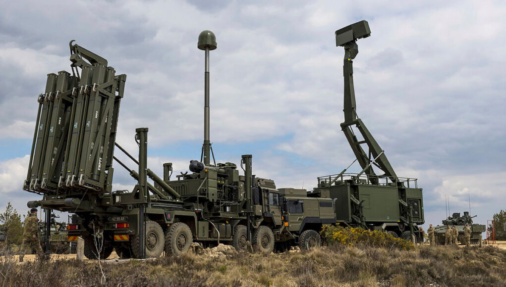 APOWMID-Official-20210428-016-0258.jpg.iCft_K6DMvOFWWtjYBMA.h60hMp0hn6 Military mobile missile system on a truck with multiple vertical launch tubes, in a dry open area under a cloudy sky.