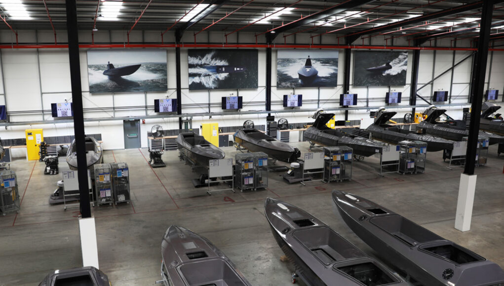 AREA 2 Industrial boat factory with row of speedboats on workbenches and tools along the wall