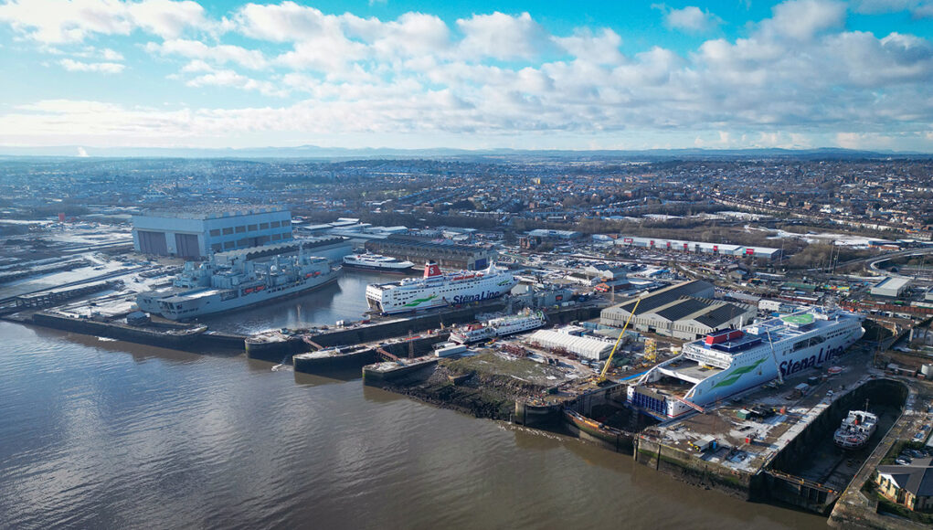 Aerial view of a harbor with large Stena Line ferries docked at a shipyard and warehouses nearby on the quay.