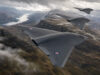 Three RAF flying-wing aircraft in formation above a winding fjord and rugged mountains in the distance.