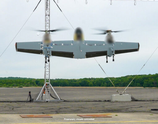 Sikorsky’s Nomad 100 drone completes first flight tests Three-rotor unmanned aircraft mounted on a test stand with supporting cables on a runway and a tree line in the background.