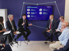 Panel discussion with six professionals in a blue-walled conference room, microphones in hand, a large screen behind shows 'Engineering the future'.