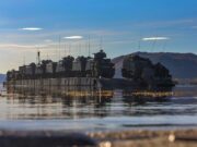 D-Day commando name revived as CLR becomes 48 Commando Armored military vehicles loaded on a flat-bottom landing craft afloat on calm water with hills in the distance.