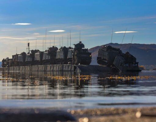 D-Day commando name revived as CLR becomes 48 Commando Armored military vehicles loaded on a flat-bottom landing craft afloat on calm water with hills in the distance.