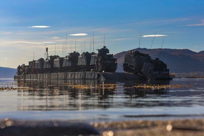 D-Day commando name revived as CLR becomes 48 Commando Armored military vehicles loaded on a flat-bottom landing craft afloat on calm water with hills in the distance.