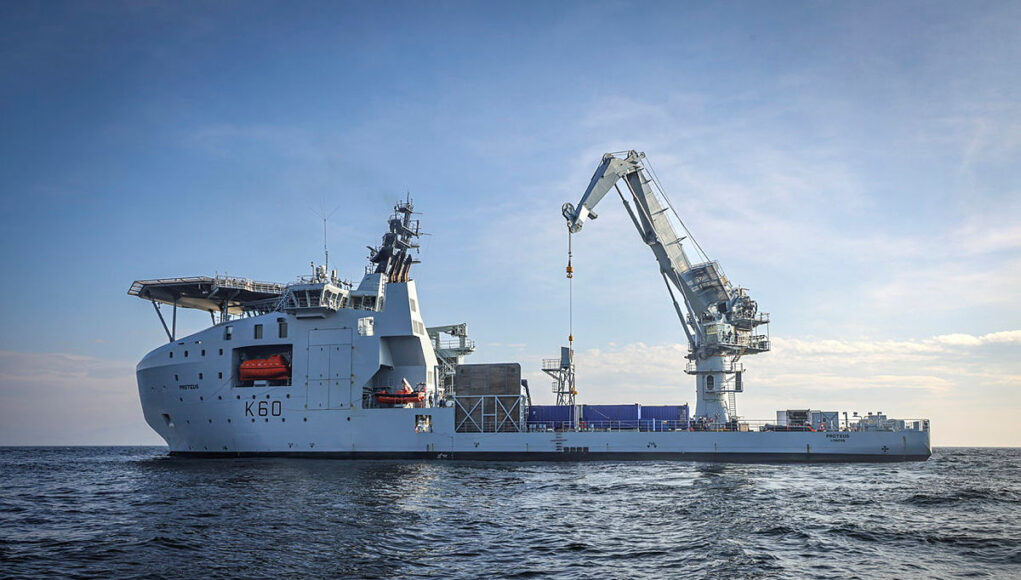 Large white offshore support vessel with a tall crane on calm blue sea, hull marked K60.