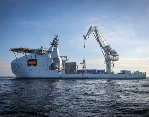 Britain’s seabed warfare vessel to get upgrades Large white offshore support vessel with a tall crane on calm blue sea, hull marked K60.