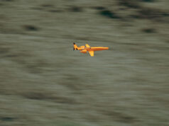 UK awards Europe’s first low-cost drone interceptor deals Small orange propeller airplane in flight over a blurred grassy landscape, viewed from the side.