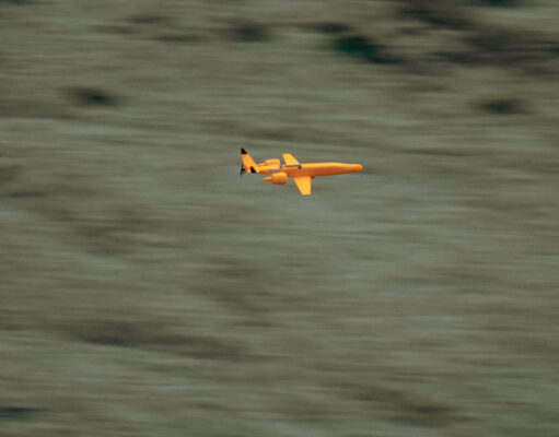 UK awards Europe’s first low-cost drone interceptor deals Small orange propeller airplane in flight over a blurred grassy landscape, viewed from the side.