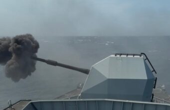 British frigate opens fire off UK coast Military vessel at sea fires its main gun, ejecting a dense black smoke plume from the muzzle.