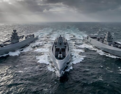 Three modern gray warships sail in rough seas, creating white wake under a stormy, sun-slashed sky.