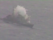 Small boat on rough water with a large white spray behind it, suggesting a splash or plume from the vessel.