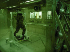 New Porton Down lab to counter biological threats Soldier in camouflage gear walking on a treadmill inside a sealed lab chamber, with a technician visible through a window in the background.