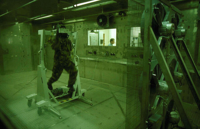 New Porton Down lab to counter biological threats Soldier in camouflage gear walking on a treadmill inside a sealed lab chamber, with a technician visible through a window in the background.