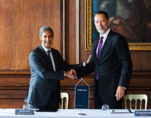 RENK to buy UK naval gearbox maker David Brown Defence Two businessmen in dark suits shake hands over a table in a wood-paneled room, with a RENK banner between them and nameplates in front of each person.