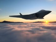 Huge new contract awarded to develop new GCAP fighter jet Sleek stealth jet flying above clouds at sunset with distant mountain horizon and a bright sun low on the horizon