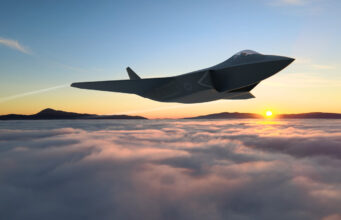 Huge new contract awarded to develop new GCAP fighter jet Sleek stealth jet flying above clouds at sunset with distant mountain horizon and a bright sun low on the horizon