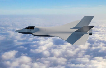 Half of new UK fighter jet demonstrator now assembled Stealth fighter jet with angular wings flying above a sea of clouds in a clear blue sky, horizon visible.