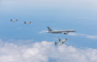 Excalibur flying testbed enters new GCAP trials phase Six gray military fighter jets flying in formation over a blue sky with white clouds.