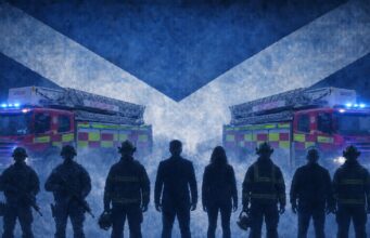Silhouetted firefighters stand in front of two ladder fire engines with blue emergency lights, against a large Scottish flag backdrop.
