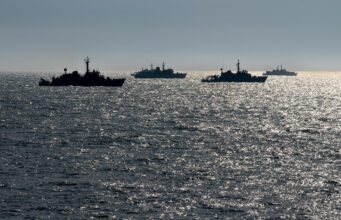 Ukrainian fleet trains with NATO off English coast Silhouetted naval ships on a glittering ocean at sunset