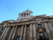Man jailed after explosives guides found on phone Facade of a grand neoclassical building with tall columns and a domed tower against a blue sky.