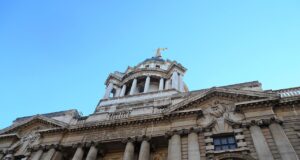 Facade of a grand neoclassical building with tall columns and a domed tower against a blue sky.