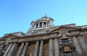 Man jailed after explosives guides found on phone Facade of a grand neoclassical building with tall columns and a domed tower against a blue sky.