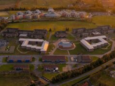 Man jailed over reconnaissance at UK military academy Aerial view of a university campus at sunset: central circular building surrounded by modern brick dorms, athletic fields, and parking lots.