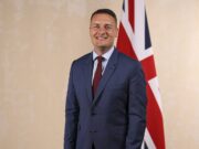 Wes Streeting appointed Defence Secretary Smiling man in a blue suit and red tie standing in front of a British flag.