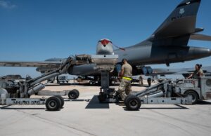 US, Australia and Marines drill mass bomb-building in Texas Ground crew service a large military aircraft on a tarmac with loading equipment and vehicles nearby under a clear blue sky.