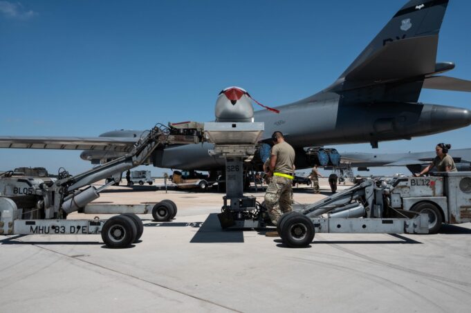 US, Australia and Marines drill mass bomb-building in Texas Ground crew service a large military aircraft on a tarmac with loading equipment and vehicles nearby under a clear blue sky.