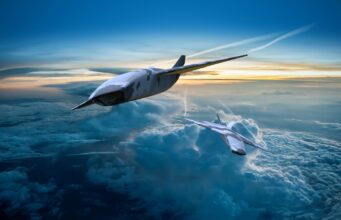 Britain’s new drone fighter may be carrier capable Two sleek, futuristic aircraft in formation above a cloud layer at sunset.