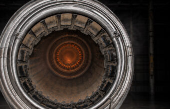 Close-up of a metallic turbine engine, concentric rings framing an orange-hot center, viewed head-on for an industrial feel