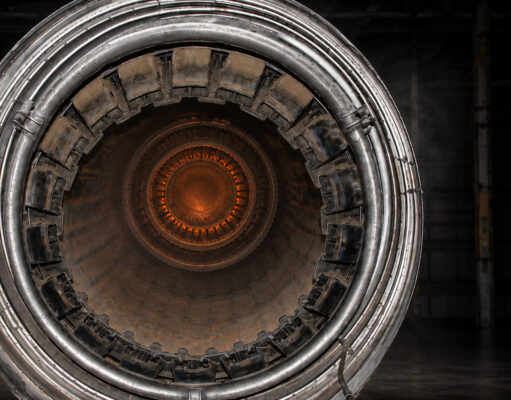 Close-up of a metallic turbine engine, concentric rings framing an orange-hot center, viewed head-on for an industrial feel