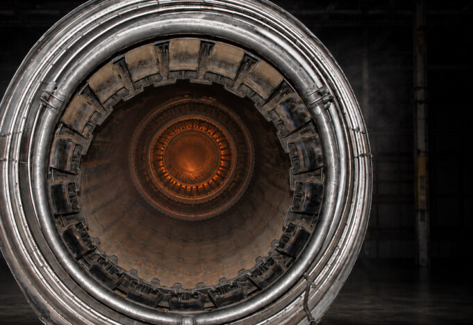 Close-up of a metallic turbine engine, concentric rings framing an orange-hot center, viewed head-on for an industrial feel