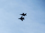 Romania shoots down second drone in two days Three silhouetted fighter jets fly in formation across a clear blue sky, with faint reflections below on the water surface.