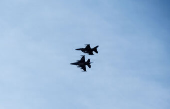 Romania shoots down second drone in two days Three silhouetted fighter jets fly in formation across a clear blue sky, with faint reflections below on the water surface.
