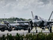 Allied air forces train elite instructors in Netherlands Front view of a stealth fighter on a runway at a military airbase, with ground crew and support vehicles in the background.