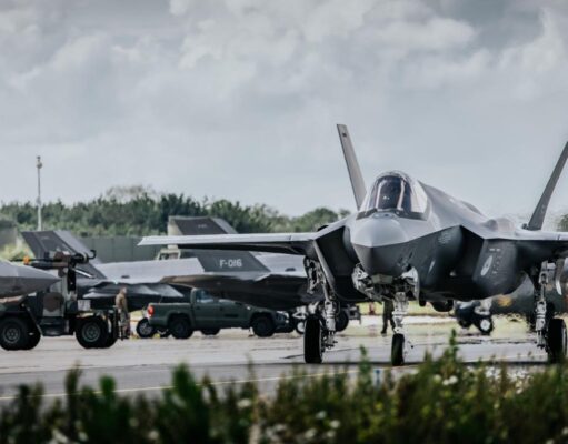 Allied air forces train elite instructors in Netherlands Front view of a stealth fighter on a runway at a military airbase, with ground crew and support vehicles in the background.