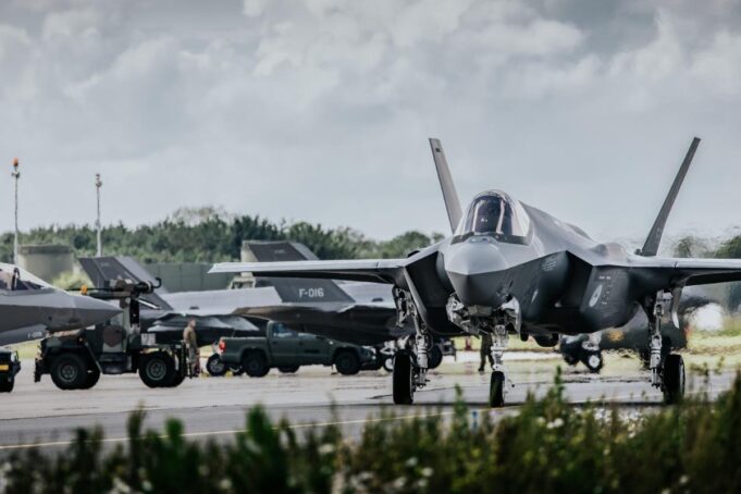 Allied air forces train elite instructors in Netherlands Front view of a stealth fighter on a runway at a military airbase, with ground crew and support vehicles in the background.
