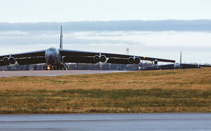 B-52 bomber taxiing on a runway at an airfield, engines visible under its long wings.