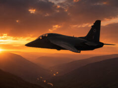 Number of new training jets for RAF still undecided Two-seat military trainer jet silhouetted against a glowing orange sunset over a winding river and mountainous valleys.