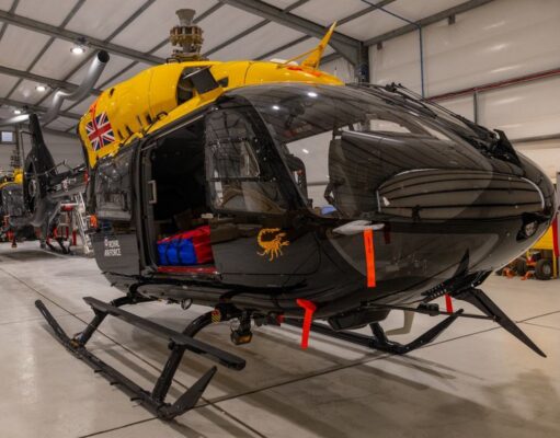 Jupiter helicopters arrive in Cyprus for 84 Squadron Military helicopters in a spacious hangar; a black helicopter in the foreground with a bright yellow top and a Union Jack emblem on its side
