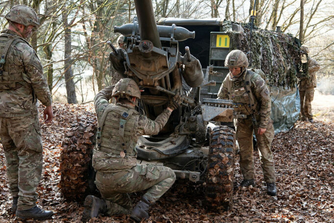BAE inks deal for Light Gun production inside Ukraine Soldiers in camouflage work on a large artillery piece in a leaf-covered forest.