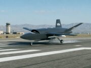 MGI Engineering unveils Vortex drone for StormFighter bid Unmanned military drone taxiing on a runway with a control tower and desert mountains in the background.