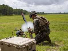 US approves Switchblade drone sale to Greece Soldier in camouflage kneels in a grassy field, handling a portable rocket launcher with a large rugged equipment case nearby.