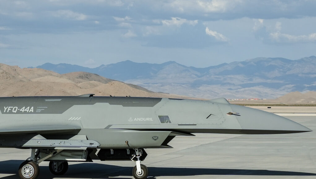 260720-F-NV774-1009 Close-up side view of a gray military jet on a taxiway, with arid mountains in the distance under a blue sky with clouds.